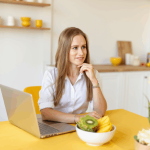 1 a photo of a female nutritionist sitting waist deep at a bright yellow table and typing on an ele ytlus1udstij8c1xfv76 2